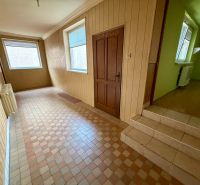 Ein Flur in einem Einfamilienhaus mit Fliesen, hellen Wänden und einem Fenster mit Jalousien.