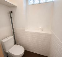Eine Toilette mit weißen Fliesen und einer Rolle Toilettenpapier in einem Einfamilienhaus.