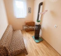 Ein Zimmer in einem Einfamilienhaus mit einem Boden in Holzoptik, einem Sofa und einem Kachelofen.