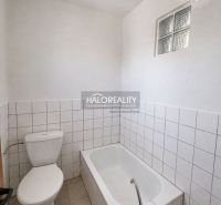 Badezimmer im Einfamilienhaus mit Badewanne, Toilette und weißen Fliesen.