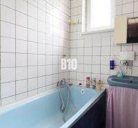 Badezimmer mit Badewanne und Waschbecken in einem Einfamilienhaus. Weiße Fliesen und hellblaue Badewanne.