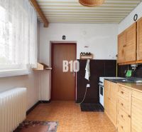 Küche in einem Einfamilienhaus mit Holzdekor und weißen Vorhängen.