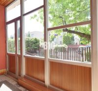 Eine verglaste Veranda mit Blick auf den Hof in einem Einfamilienhaus.