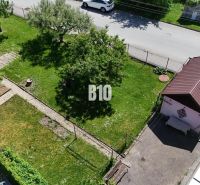 Ein Garten mit Rasen bei einem Einfamilienhaus in Martin, man sieht einen Baum, einen Gartenweg und einen Unterstand.