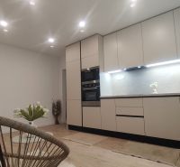 Küche in einer 4-Zimmer-Wohnung mit Holzboden, weißen Schränken und Pflanzen.