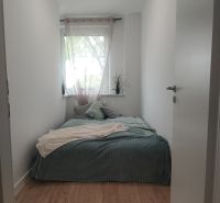 Schlafzimmer mit Bett, weißen Wänden und Boden in Holzoptik in einer 4-Zimmer-Wohnung.