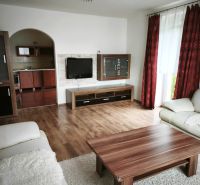 Wohnzimmer in einem Einfamilienhaus mit Sofa, Tisch und Boden in Holzoptik.