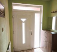 Eingangstür im Einfamilienhaus mit weißem Rahmen und Fliesen mit Dekor.