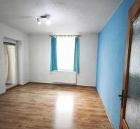 Ein Zimmer in einem Einfamilienhaus mit einer blauen Wand und einem Boden in Holzoptik.