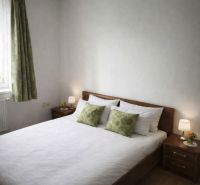 Ein Schlafzimmer in einem Einfamilienhaus mit einem Doppelbett, einem Boden in Holzoptik und dekorativen Kissen.
