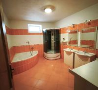 Ein Badezimmer in einem Einfamilienhaus mit orangefarbenen Fliesen, einer Badewanne und einer Dusche.