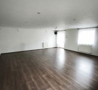 Ein geräumiges Zimmer in einem Einfamilienhaus mit Holzboden und weißen Wänden.
