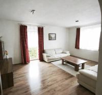 Wohnzimmer in einem Einfamilienhaus mit Sofas, einem Tisch und einem Boden in Holzoptik.