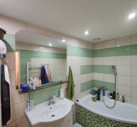 Das Badezimmer einer 3-Zimmer-Wohnung mit Badewanne, Waschbecken und Fliesen in Grüntönen.