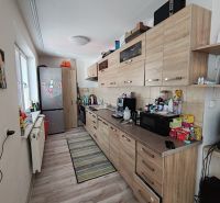 Küche mit Holzelementen in einer 3-Zimmer-Wohnung, ausgestattet mit Geräten und Stauraum.