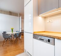 Küche mit Holzelementen, Esstisch und vier Stühlen in einer 2-Zimmer-Wohnung.