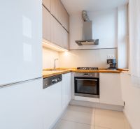Küche in einer 2-Zimmer-Wohnung mit weißen Schränken und Holzelementen.