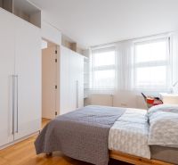 Helles Schlafzimmer in einer 2-Zimmer-Wohnung mit Schränken und Bett, Boden mit Holzdekor.