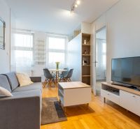 Wohnzimmer mit Holzboden, Sofa und Esstisch in einer Zweizimmerwohnung.