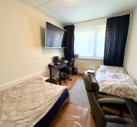 Ein Zimmer in einer 4-Zimmer-Wohnung mit zwei Betten, Holzboden und einem Schreibtisch.