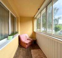 Balkon einer 4-Zimmer-Wohnung mit Sitzgelegenheit und Boden in Holzoptik.