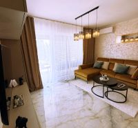 Wohnzimmer in einer 2-Zimmer-Wohnung mit glänzenden Fliesen und einem Sofa.