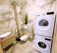 Badezimmer mit Waschmaschine und Trockner in einer 2-Zimmer-Wohnung mit Marmorverkleidung.