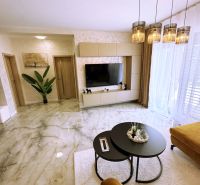 Wohnzimmer in einer Zweizimmerwohnung mit Marmorboden und stilvoller Beleuchtung.