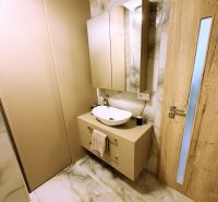Badezimmer mit Schrank und Waschbecken, Fliesen mit Marmormuster, Holztüren.