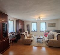 Wohnzimmer in einem Einfamilienhaus mit Holzbodenoptik und bequemen Sitzgelegenheiten.