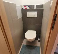Kompakte Toilette mit Fliesen und Teppich in einer 3-Zimmer-Wohnung.