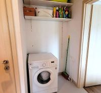 Waschmaschine mit Regalen für Reinigungsmittel und Mopp in einer 3-Zimmer-Wohnung.
