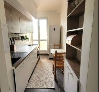Eine schmale Küche in einer 3-Zimmer-Wohnung mit weißen Schränken und dunklem Boden.
