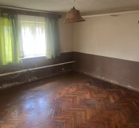 Ein Zimmer in einem Einfamilienhaus mit einem Holzboden und grünen Vorhängen.