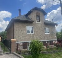 Ein Einfamilienhaus in Rudná mit einer zweistöckigen Fassade, einem eingezäunten Grundstück und blauem Himmel.