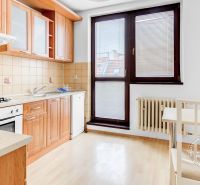 Eine Küche mit Holzelementen in einer 2-Zimmer-Wohnung enthält eine Essecke und Elektrogeräte.