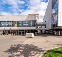 Einkaufszentrum in Bratislava mit Gastronomiebereich und Außensitzplätzen vor dem Café.