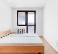 Schlafzimmer in einer 2-Zimmer-Wohnung mit Bett, Nachttisch und Fenster.