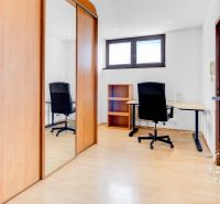 Arbeitsbereich in einer 2-Zimmer-Wohnung mit Holzboden und einem Schrank mit Schiebetüren.