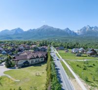 Ein Blick auf Hotels und Pensionen in Nová Lesná mit der Hohen Tatra im Hintergrund.