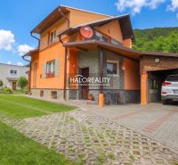 Einfamilienhaus in Dolná Mariková mit Garage, Rasen und Parkfläche vor dem Haus.