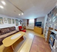 Wohnzimmer in einem Einfamilienhaus mit einem Steinkamin und einem Boden in Holzoptik.