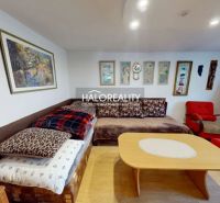 Wohnzimmer in einem Einfamilienhaus mit Sofa, Sesseln und Bildern an den Wänden, Boden mit Holzdekor.