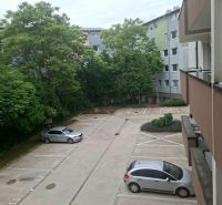 Parkplatz in der Športová-Straße in Dunajská Lužná mit Autos und Grün im Hintergrund.