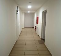 Chodba mit weißen Wänden, Fliesen und Notfallausrüstung im Einzimmerapartment.