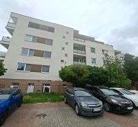 Wohnhaus in der Športová-Straße in Dunajská Lužná mit Parkplatz und Autos vor dem Gebäude.