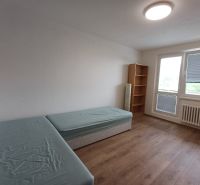 Ein Zimmer mit zwei Betten, einem Regal und einem Boden mit Holzdekor in einer 3-Zimmer-Wohnung.