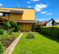 Garten und Einfamilienhaus in Slovenská Ľupča mit gepflegtem Rasen und Blumenbeeten.