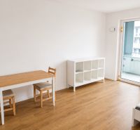 Wohnzimmer in einer Einzimmerwohnung mit Holzboden und Esstisch.