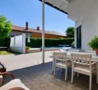 Die Terrasse des Einfamilienhauses in Žabokreky mit weißen Möbeln und Grünpflanzen.